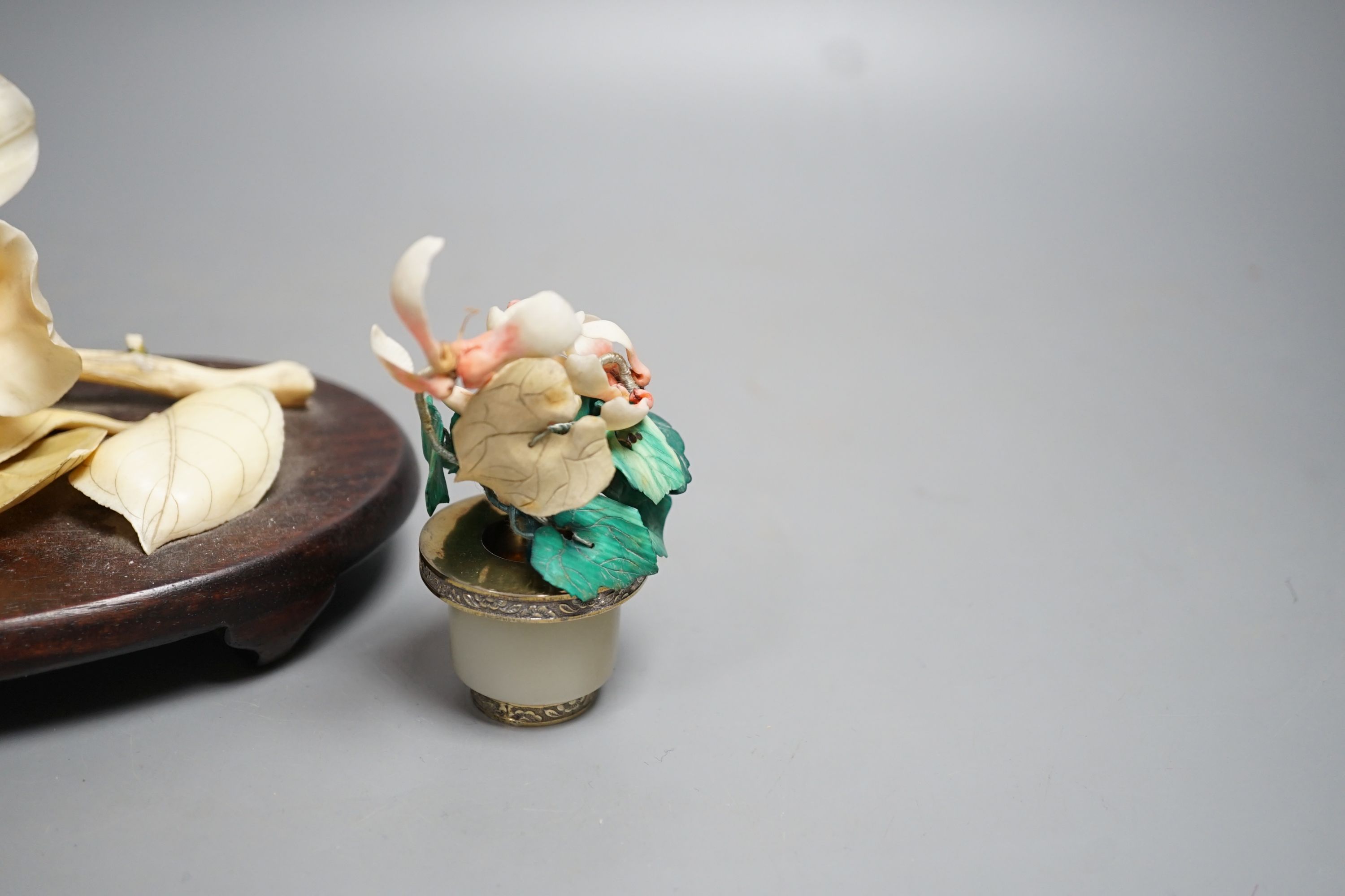 A Chinese ivory model of a peony flower on stand and a Chinese coloured ivory model of flowers with a white jade and white metal plant pot, first half 20th century. Largest measurement 19cm